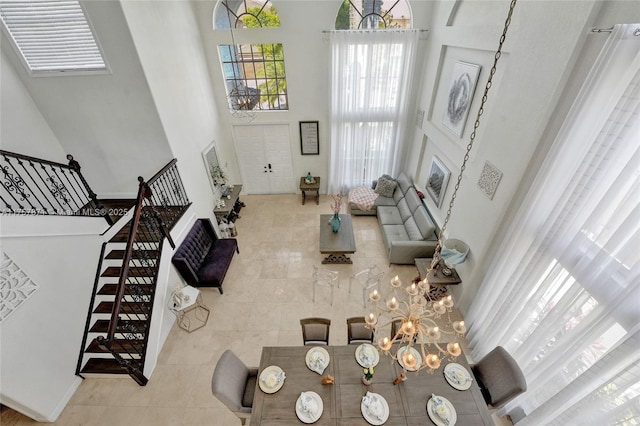 living area featuring tile patterned floors, a notable chandelier, a high ceiling, and stairs