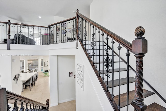 stairway with tile patterned flooring and a high ceiling