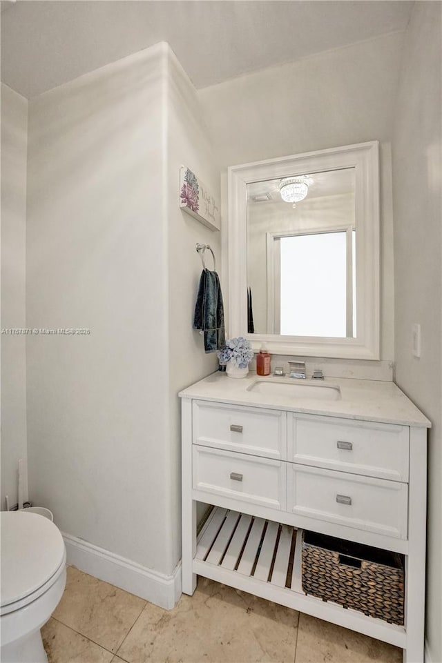 bathroom with toilet, tile patterned flooring, baseboards, and vanity