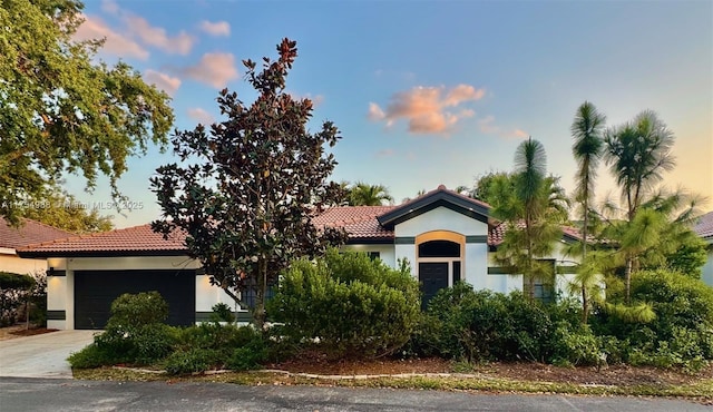 mediterranean / spanish-style home featuring a tiled roof, stucco siding, driveway, and an attached garage