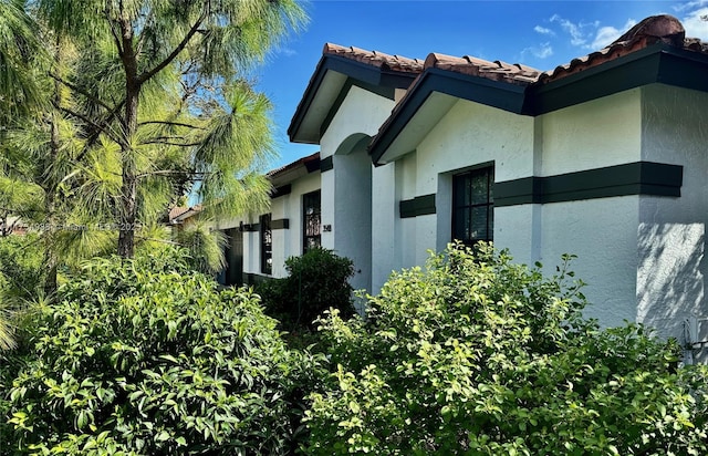 view of property exterior with stucco siding and a tiled roof