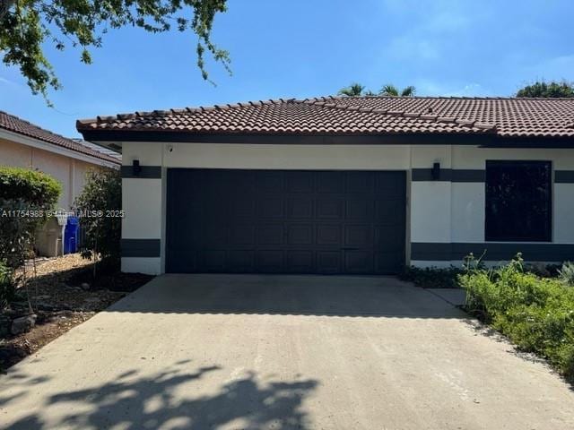 view of front of property with stucco siding, concrete driveway, and a tiled roof