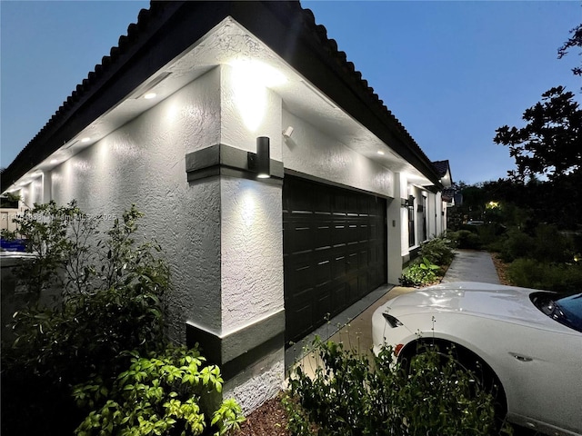 view of side of home with stucco siding and a tiled roof