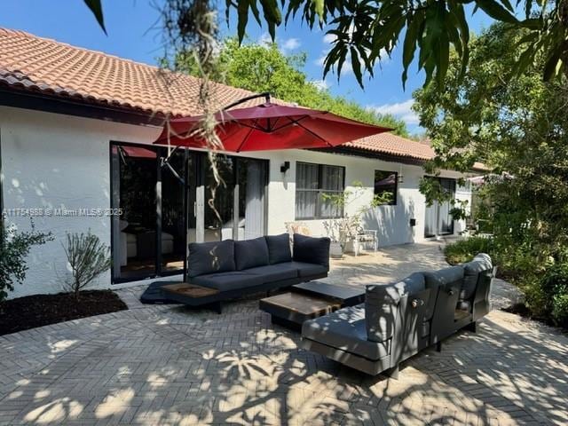 back of house with stucco siding, an outdoor hangout area, a patio area, and a tile roof