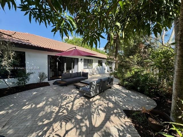 rear view of house featuring stucco siding, a tiled roof, outdoor lounge area, and a patio