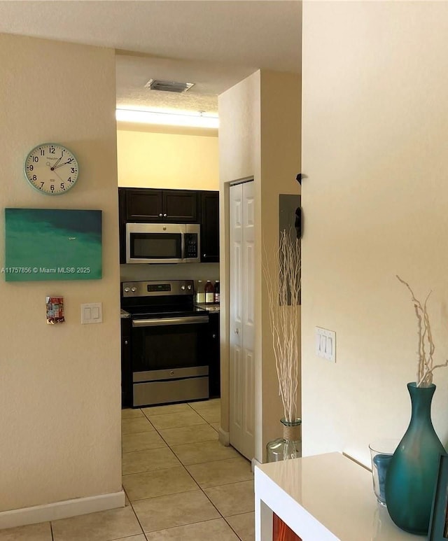 kitchen featuring appliances with stainless steel finishes, light tile patterned flooring, visible vents, and baseboards