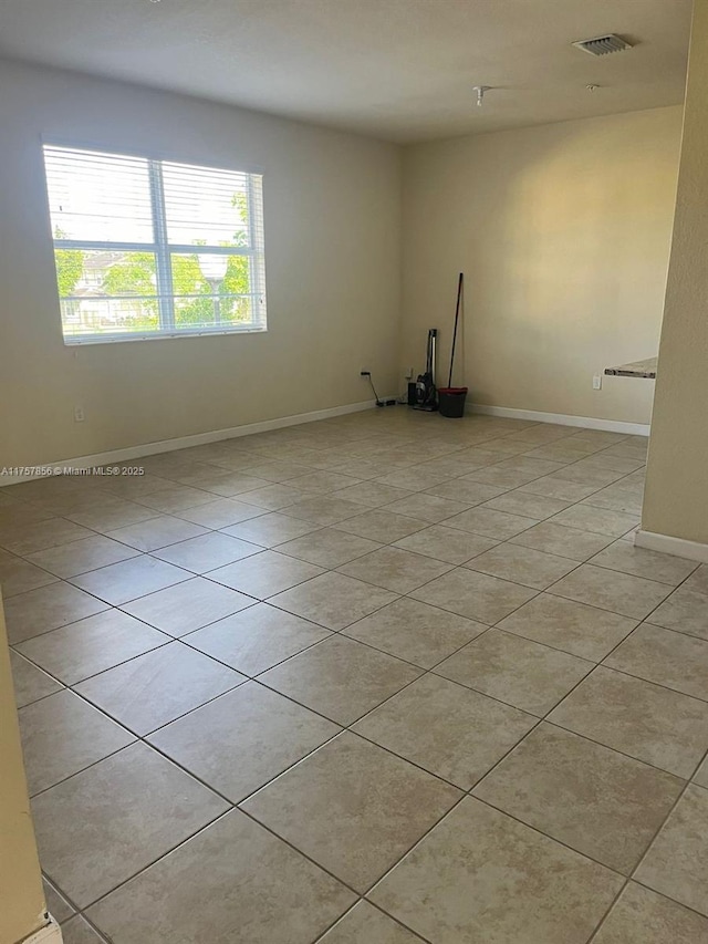 spare room with light tile patterned floors, visible vents, and baseboards