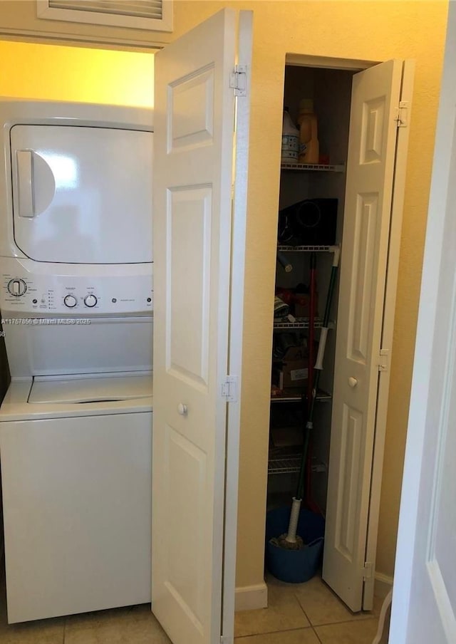 laundry area with stacked washer / drying machine, laundry area, and light tile patterned floors