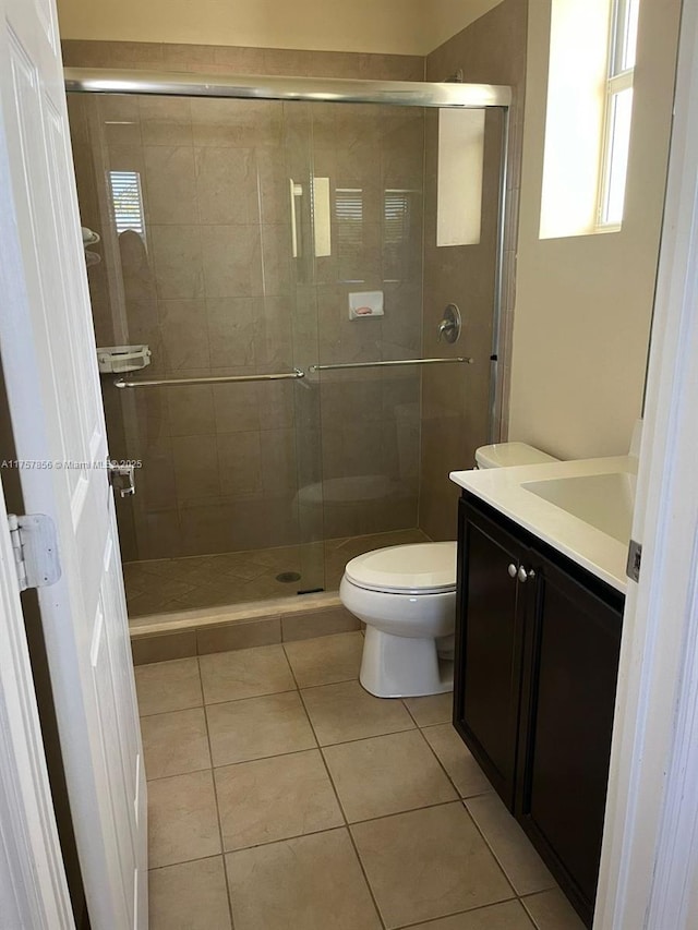 full bathroom with a stall shower, vanity, toilet, and tile patterned floors