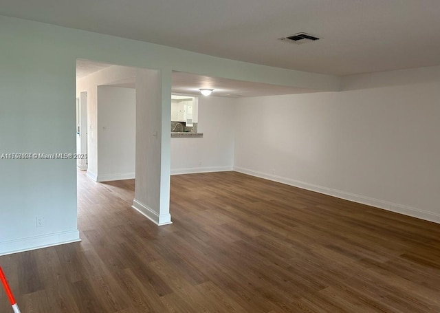 finished below grade area with dark wood-type flooring, visible vents, and baseboards