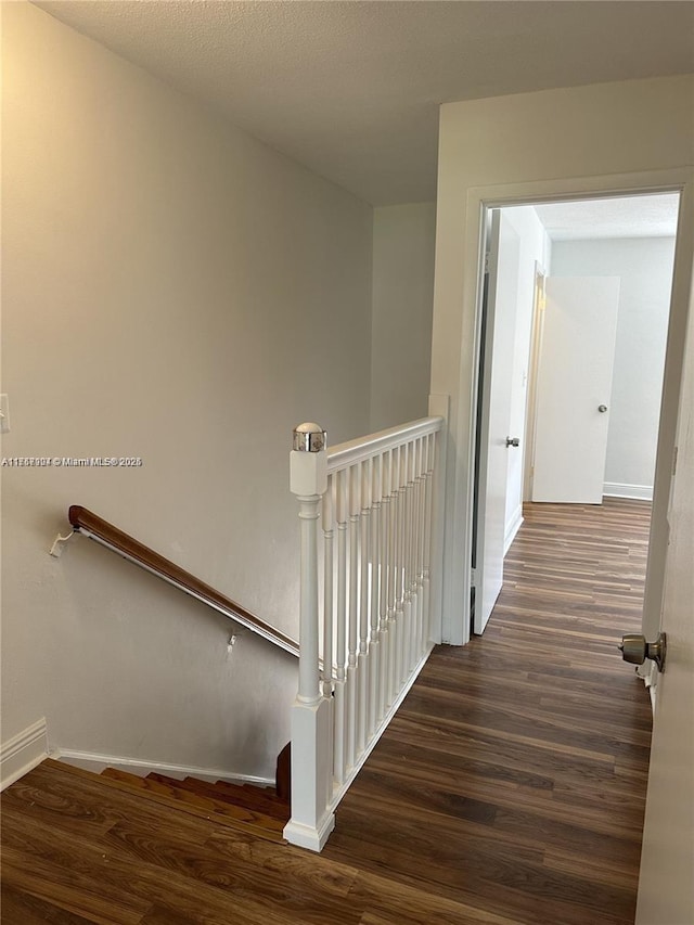 staircase featuring baseboards and wood finished floors