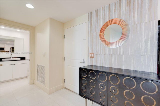 corridor featuring light tile patterned floors, baseboards, visible vents, a sink, and recessed lighting