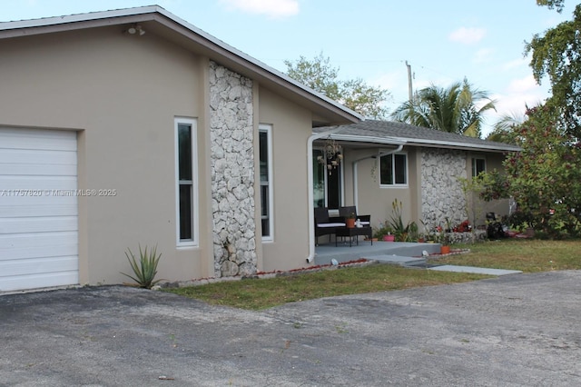 exterior space with a garage, stone siding, and stucco siding