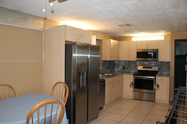 kitchen with light tile patterned floors, stainless steel appliances, a sink, visible vents, and backsplash