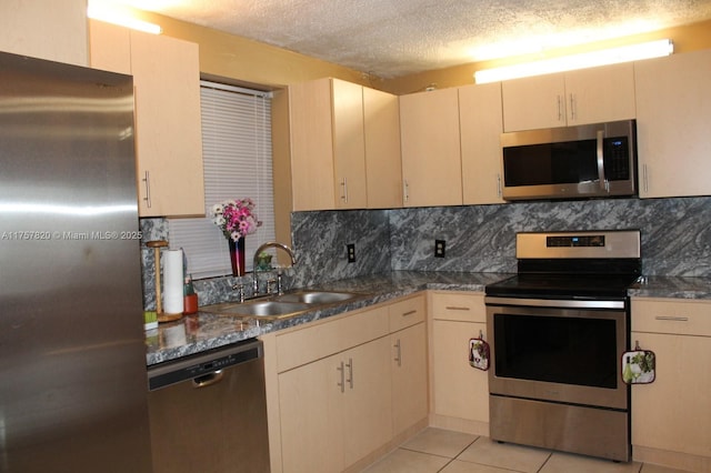 kitchen featuring light tile patterned floors, stainless steel appliances, tasteful backsplash, a sink, and a textured ceiling