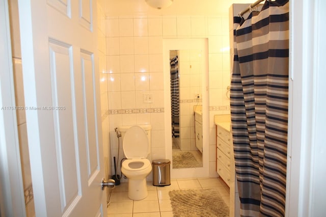 bathroom with toilet, curtained shower, tile patterned flooring, and tile walls