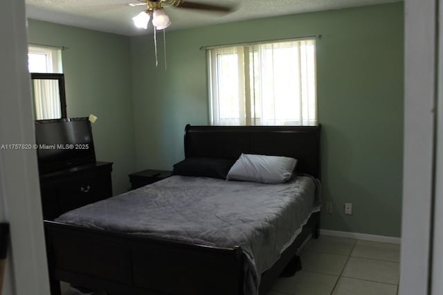 bedroom with multiple windows, baseboards, a textured ceiling, and light tile patterned flooring