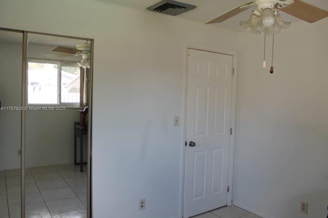 empty room with light tile patterned floors, ceiling fan, and visible vents