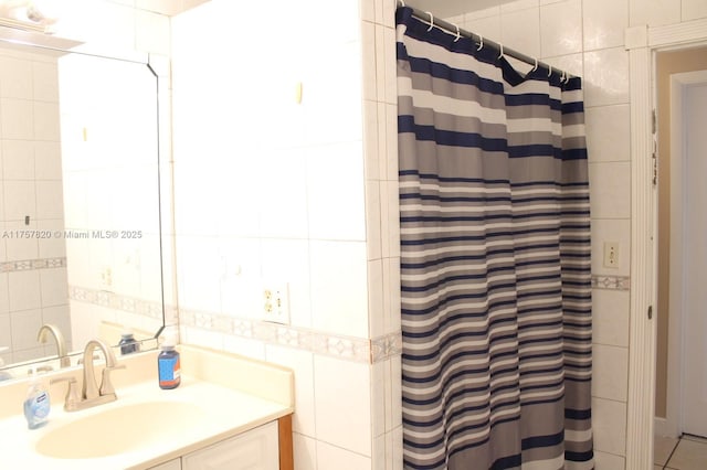 full bath with a shower with shower curtain, tile walls, and vanity