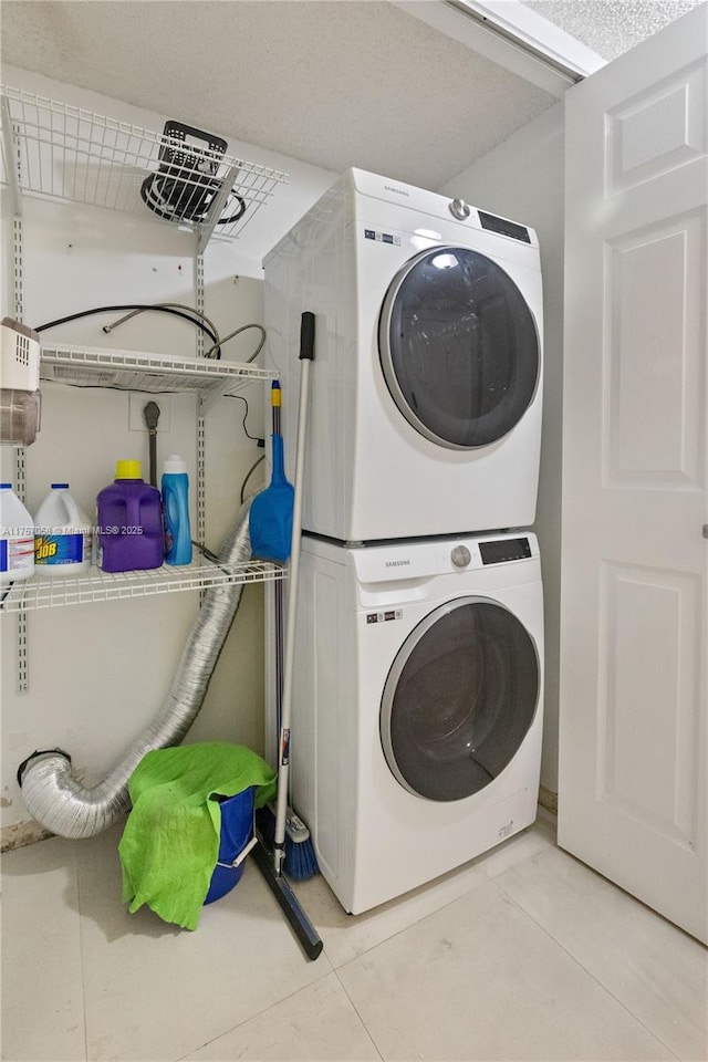 laundry area featuring laundry area, stacked washing maching and dryer, and light tile patterned floors