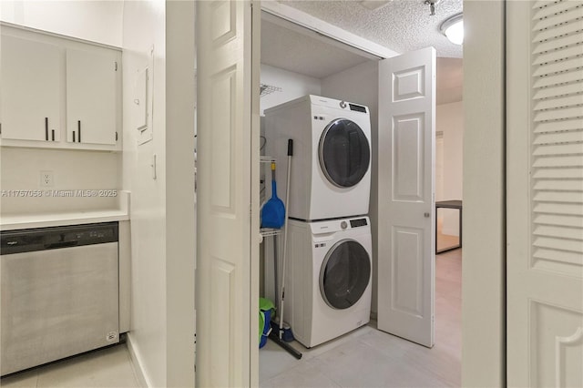 laundry room with stacked washer and dryer, laundry area, a textured ceiling, and light tile patterned floors