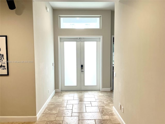 entryway with stone tile floors, baseboards, and french doors