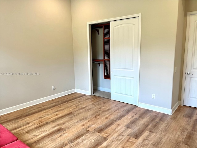 unfurnished bedroom with a closet, wood finished floors, and baseboards