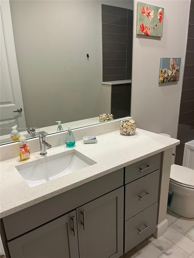 bathroom with marble finish floor, vanity, and toilet