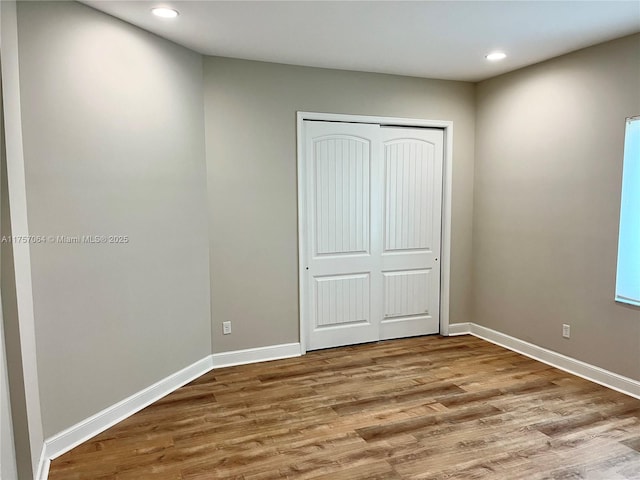 unfurnished bedroom featuring recessed lighting, a closet, baseboards, and wood finished floors