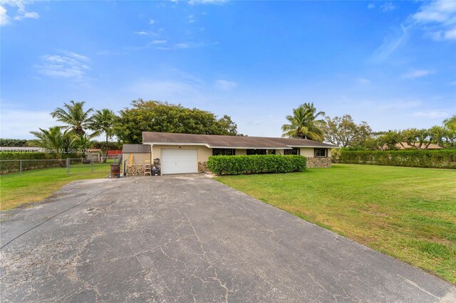 view of front of home with a garage, fence, driveway, stucco siding, and a front yard