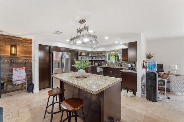 kitchen featuring dark brown cabinetry, a kitchen bar, a kitchen island, and stainless steel appliances