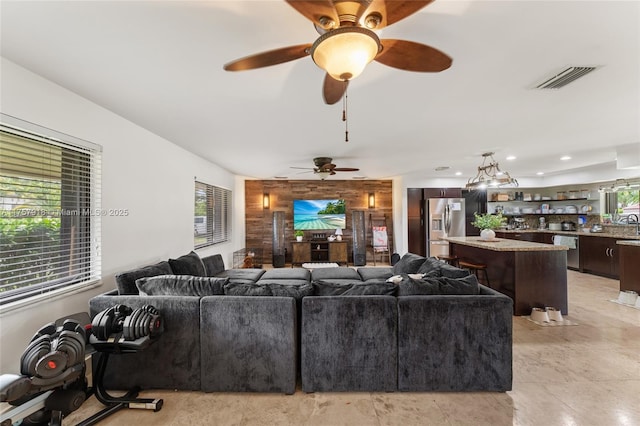 living area featuring an accent wall, wood walls, visible vents, and recessed lighting