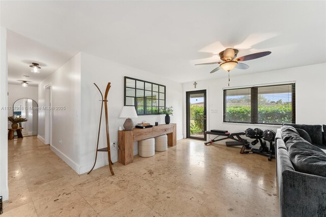 living room with ceiling fan and baseboards