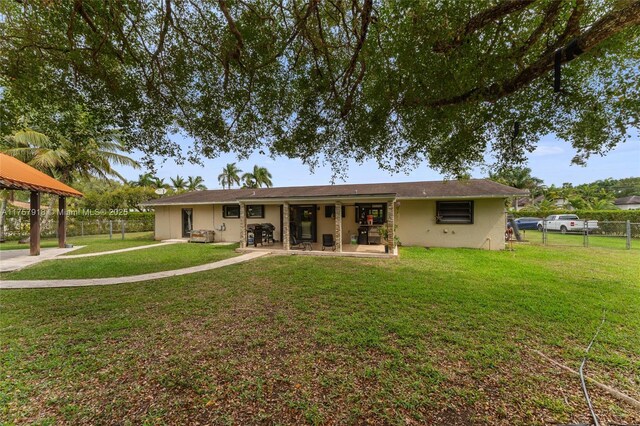 rear view of property featuring a yard, fence, a patio, and stucco siding