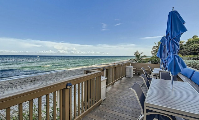 wooden deck featuring a beach view and a water view