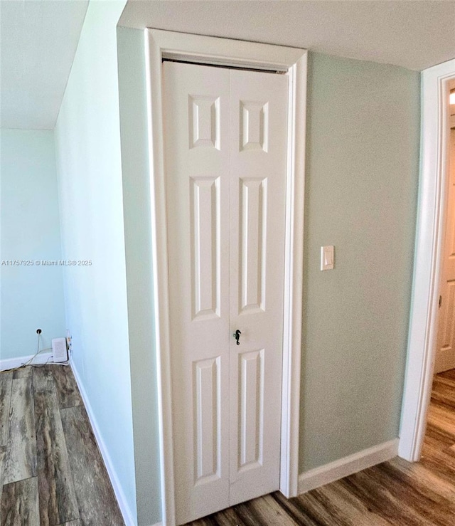 interior space featuring baseboards and dark wood-style flooring