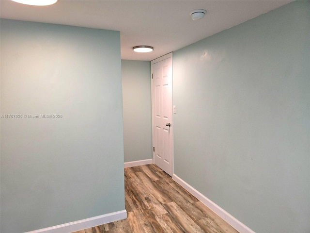 corridor with baseboards and wood finished floors