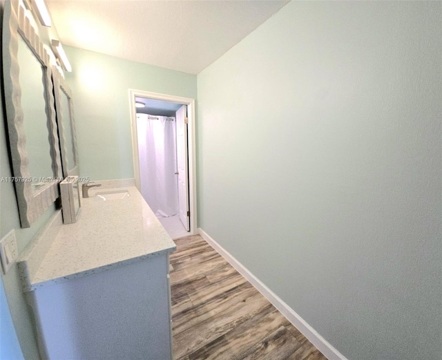 bathroom featuring baseboards, wood finished floors, and vanity