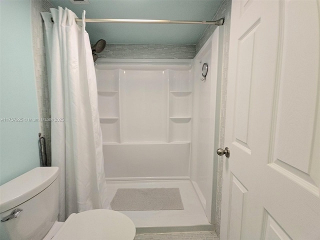 full bathroom featuring a shower stall and toilet