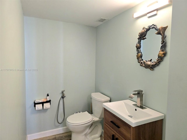 bathroom featuring visible vents, toilet, vanity, wood finished floors, and baseboards