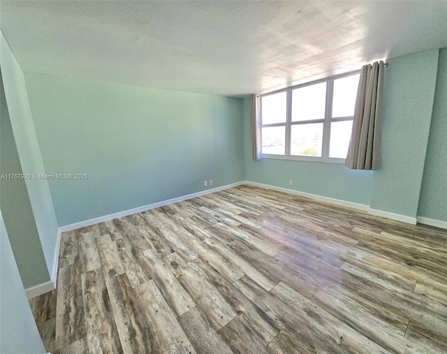 unfurnished room with wood finished floors and baseboards