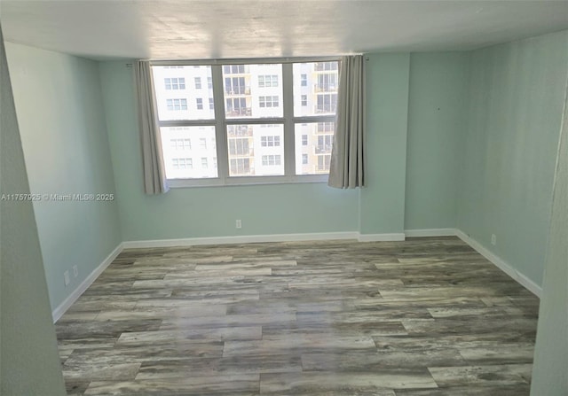 spare room featuring wood finished floors and baseboards