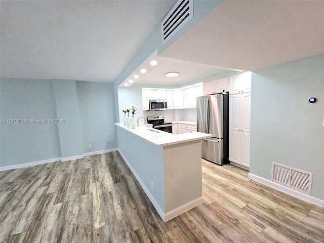 kitchen with a peninsula, light wood-style flooring, visible vents, and stainless steel appliances