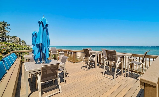 deck with outdoor dining area and a water view