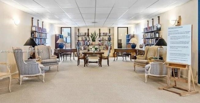 sitting room with a paneled ceiling and carpet flooring