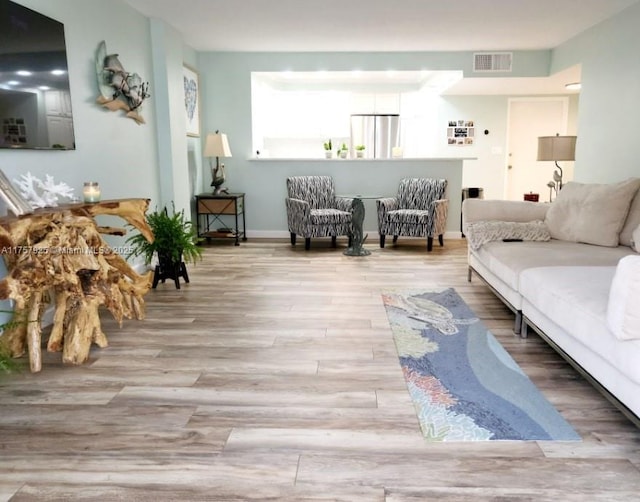 living area with baseboards, visible vents, and wood finished floors