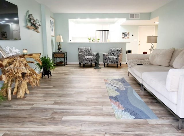 living area with wood finished floors, visible vents, and baseboards