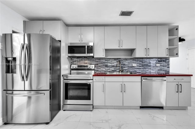 kitchen featuring visible vents, marble finish floor, stainless steel appliances, open shelves, and a sink