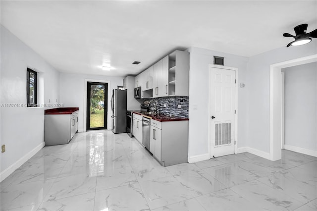 kitchen featuring marble finish floor, dark countertops, backsplash, and visible vents