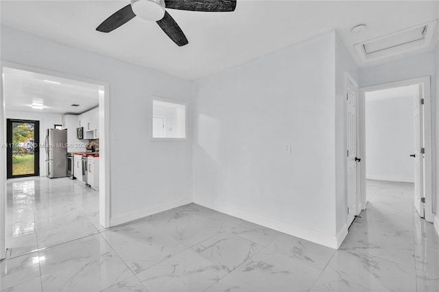 empty room featuring attic access, marble finish floor, baseboards, and a ceiling fan